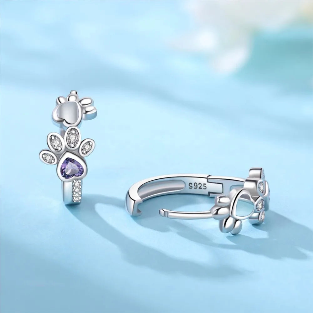 Silver paw print earrings with zirconia and a heart-shaped gemstone.
